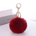 Detailed view of an 8cm red faux rabbit fur pom pom keychain with a gold metal clasp - Burgundy