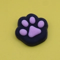 Squishy black cat paw stress relief toy with pink pads on a yellow background - Black and Pink Cat Paw