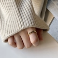 Anello conico dorato minimalista indossato da una modella con maglione in maglia beige - Superficie quadrata piatta / Oro