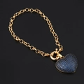 Goldenes Armband mit funkelndem blauen Zirkon-Herzanhänger auf schwarzem Hintergrund - Blau