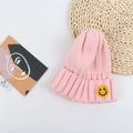 Close-up of pink ribbed beanie with yellow smiley face patch on a decorative flat lay - 50-56cm / Pink