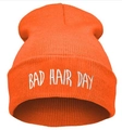 Detail of bright orange knitted beanie featuring white Bad Hair Day embroidery texture - Orange