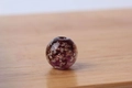 Einzelne lila leuchtende Glasperle mit Goldglitzer und weißen Punkten auf Holz - 6mm / Lila