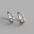 Détail de créoles en argent 925 avec zircons rectangulaires et ronds sur fond gris neutre - Or Blanc