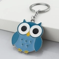Blue owl enamel keychain with silver ring on minimalist white display stand - Blue