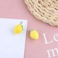 Dettaglio macro di ciondolo a forma di limone in resina gialla con foglia verde - Limone