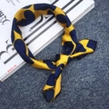 Elegant yellow silk scarf with navy blue pop patterns placed on a fashion magazine - Heart Yellow