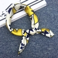 Neck scarf with yellow and navy clover print tied on a blue textured background - Four Leaf Clover Yellow