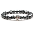 Macro detail of hematite beads and silver skull charm with red gemstone eyes on a bracelet - White K/Silver