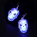 Gros plan de boucles d'oreilles crâne avec lumières LED bleues sur fond sombre - Boucles d'oreilles tête de mort / Lumière bleue