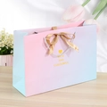 Pink and blue gradient gift bag with gold ribbon bow on a wooden surface - 14x7x15cm / Gradient Blue Pink-Gold Ribbon (Gold Heart)