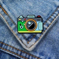 Bunte Kamera-Emaille-Anstecknadel auf Jeansjacke mit Wald- und Camping-Themendesign - Kamera