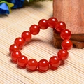 Macro shot of semi-transparent red agate bead bracelet on natural bamboo and wood background - 14mm