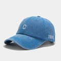 Detail view of washed blue denim baseball cap featuring white C and 1999 embroidery - Adjustable / Blue