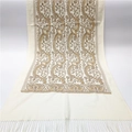 Detailed close-up of beige pashmina shawl with gold paisley embroidery and fringe trim - White