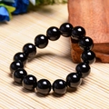 Polished natural black agate beaded bracelet displayed on a bamboo and wooden background - 14MM Natural Black Agate
