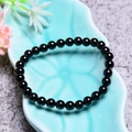 Polished natural black agate beaded bracelet displayed in a blue leaf-shaped ceramic dish - 6MM Natural Black Agate