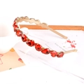 Dettaglio del cerchietto in metallo dorato con strass rossi a goccia su sfondo bianco - Strass Rosso a Goccia