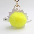 Detail of yellow plush pom-pom dinosaur keychain with iridescent leather and gold ring - Yellow