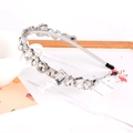 Dettaglio ravvicinato di un cerchietto sottile con strass e base argento su marmo - Strass Bianco Forme Miste
