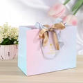 Pink and blue gradient gift bag with a double ribbon bow on a wooden surface - 14x7x15cm / Gradient Blue Pink-Bicolor Ribbon (Gold Heart)