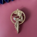Dettaglio macro della spilla vintage in oro opaco con figura d'angelo e perla bianca fine - Ragazza Sognante