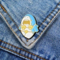 Detail van een emaille speld cartoon haai met gouden bikini op blauwe denim stof - Bikini Haai