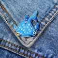 Close-up of a blue enamel whale shark brooch with light blue spots on denim fabric - Spotted Whale Shark