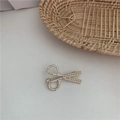 Dettaglio ravvicinato di una spilla dorata a forma di forbici con perle e strass scintillanti - Stile Forbici Strass Perla