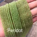 Strands of faceted peridot gemstone beads in bright grass green held by hand - Peridot 3mm