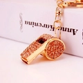 Golden whistle keychain with sparkling amber rhinestones on an elegant book background - Peach