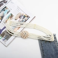 Close-up of a four-row pearl belt with a round gold rhinestone buckle on a blue denim - Large Round Center Rhinestone Pearl Buckle (Gold)