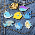 Collection of eight colorful ocean animal enamel pins pinned on blue denim fabric - Marine Life Collection