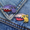 Cute enamel cuttlefish pins in purple and pink variants pinned on blue denim fabric - Cuttlefish Collection Set