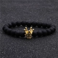 Gros plan d'un bracelet en perles noires mates avec un pendentif couronne dorée et zircons - Noir Mat Couronne Dorée