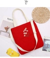 Detail of red corduroy tote with daisy embroidery and adjustable straps on white background - Red