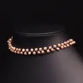 Elegantes Zickzack-Halsband aus rosa-orangefarbenen Naturperlen auf einem schwarzen Ständer - Lila