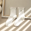 Weiße Rippsocken mit Gänseblümchen-Stickerei und Rüschenrand in weichem Licht - Einheitsgröße / Weiß