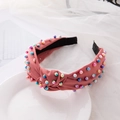 Pink knotted headband with colorful imitation pearls displayed on a white ceramic plate - Hot Pink