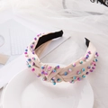 Beige knotted fabric headband decorated with colorful beads on a white display plate - Beige