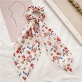 Detalle de un coletero de gasa floral con cintas largas y estampado de flores vibrantes - Cinta Blanca de Flores