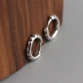 Vista macro di orecchini a cerchio in argento a forma di ingranaggio con diamanti - Oro Bianco (1 Paio)