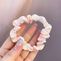 Handheld shot of a soft pink satin silk hair scrunchie with smooth pleated fabric texture - Light Pink