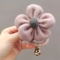 Handheld view of a pink woolen flower hair tie with golden bead and woven band - Pink Purple