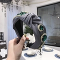 Grey knotted fabric headband featuring large emerald green stones and sparkling rhinestones - Gray