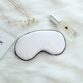 White silk sleep mask with black trim on faux fur background with lifestyle props - Adjustable Buckle Paper Card Packaging / White