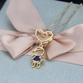 Collar con colgante de corazón dorado y niño azul sobre una cinta de raso rosa - Niño Bañado en Oro