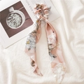Detail view of pink floral hair scrunchie with long ribbons on a minimalist fabric background - Triangle Streamer / Pink