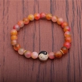 Pulsera de cuentas de ágata de 8mm con dije de yin yang sobre fondo de madera rústica - Floral Naranja