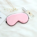 Pink silk sleep mask with black trim on white faux fur background with lifestyle props - Adjustable Buckle Paper Card Packaging / Pink